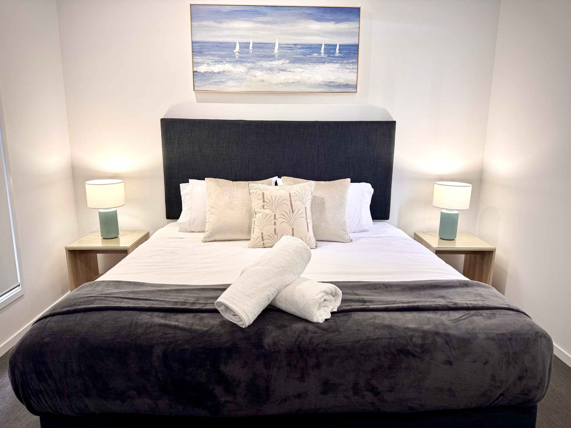 Master suite with king bed, bedside lamps and coastal artwork