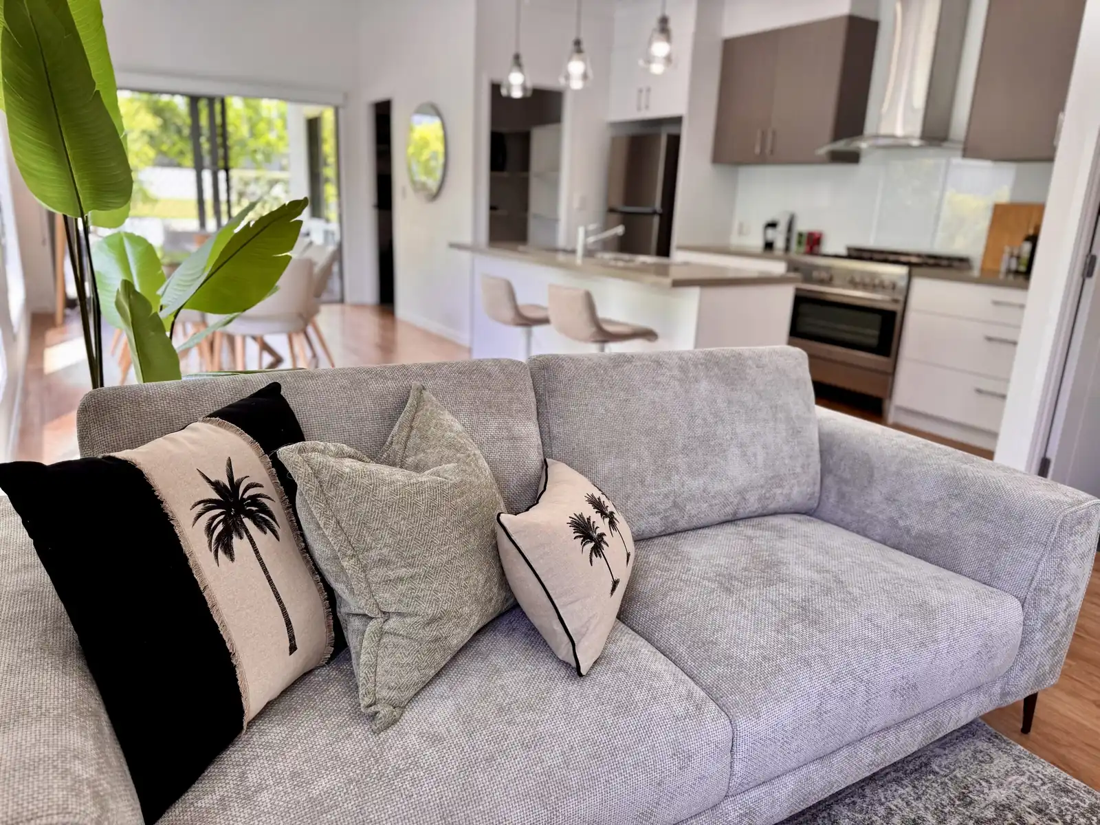 Open-plan living room with coastal palm cushions opening onto the modern kitchen at Redcliffe Seaside Villa Escape in Scarborough