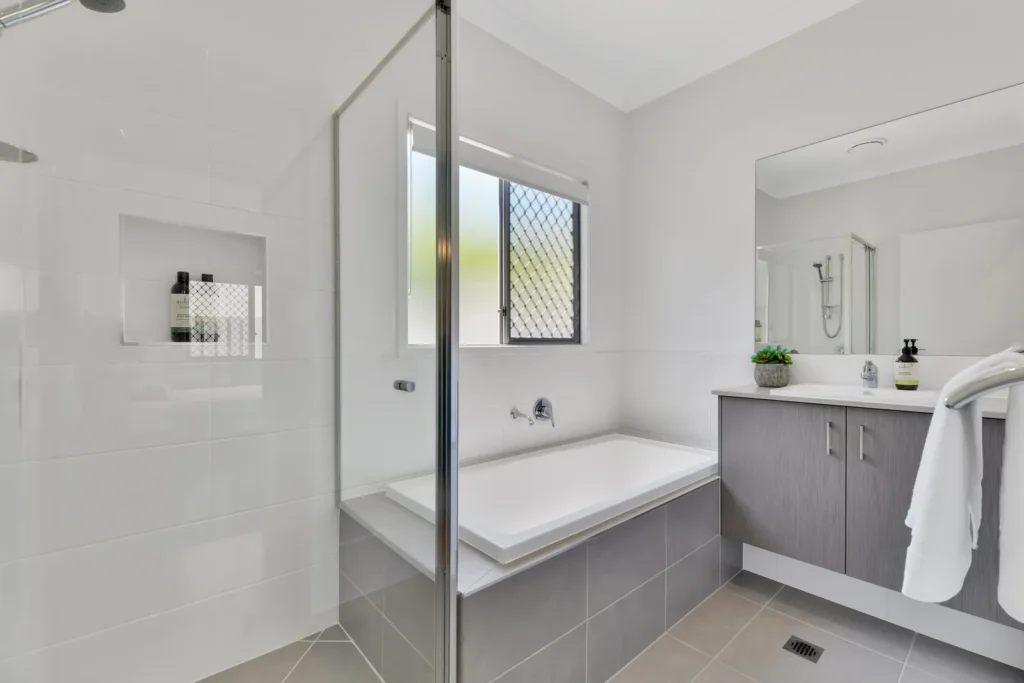 Bathroom with a built-in bathtub, glass-screened shower and vanity