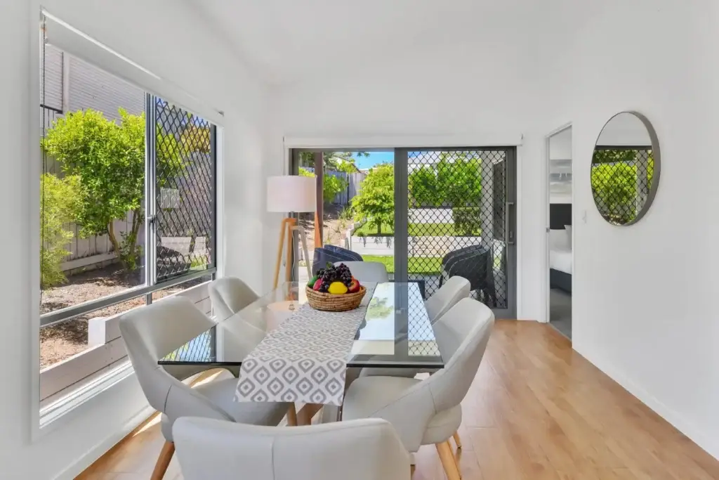 Glass-top dining table beside sliding doors that open to the back garden