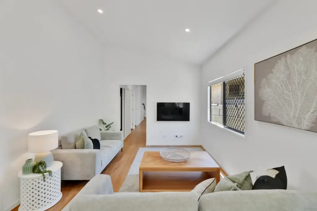 Living area with light grey sofas, timber coffee table and wall-mounted TV