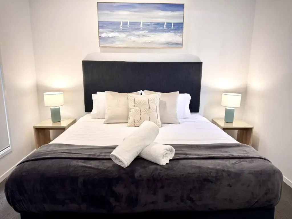 Master suite with king bed, bedside lamps and coastal artwork