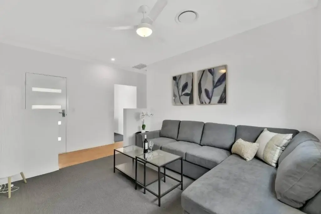 Media room with grey modular lounge, glass coffee tables and leaf-print artwork